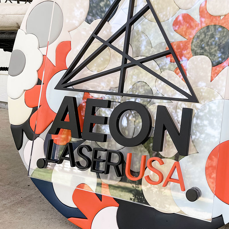 round wooden sign made of orange, blue, and white flowers with a prism and 国产视频一区二区 logo on top